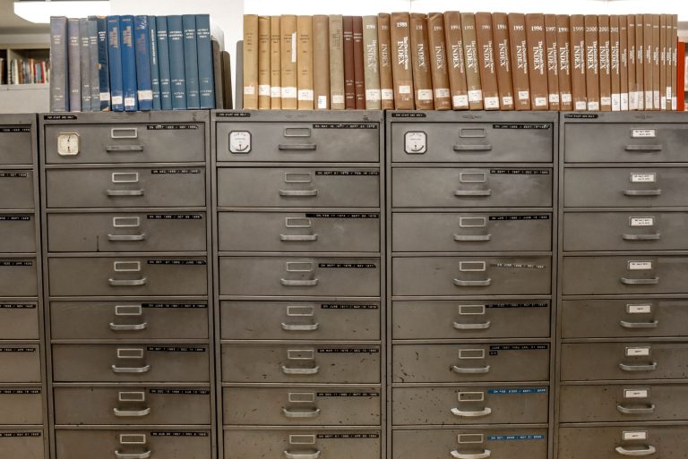 Reihen beschrifteter Aktenschränke in einem Archiv