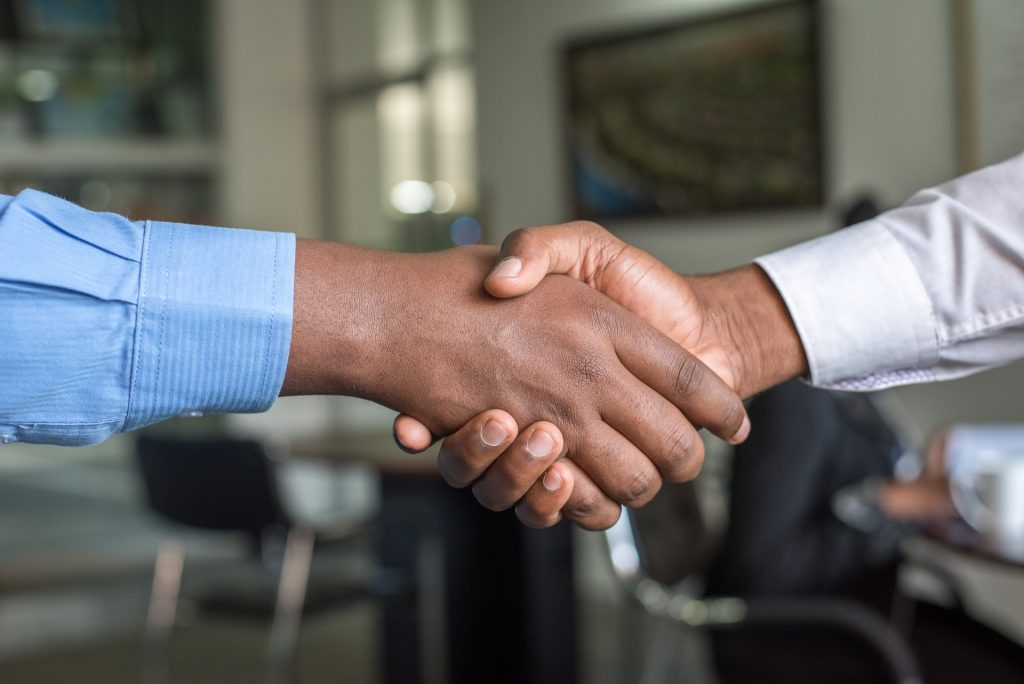 Zwei Personen geben sich in einem Büro die Hand